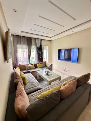 a living room with a large couch and a table at Bel appartement vue piscine in Bouznika