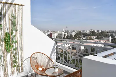 a balcony with a table and chairs and a view of a city at Bright & Cozy Apt with City View in Casablanca