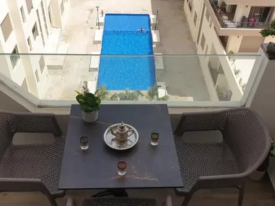 a table with chairs and a swimming pool in a building at Cozy studio with great pool views in Aïn Harrouda