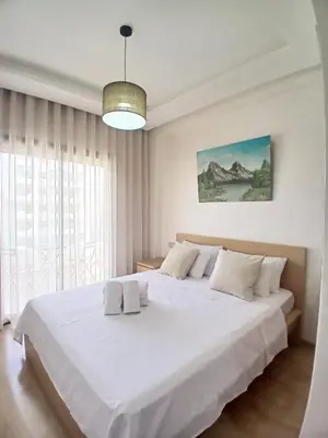 a bedroom with a large white bed with a large window at Duplex Luxe 3 Chambres Vue Mer & Piscine à Zenata Eco City in Aïn Harrouda