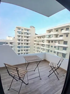 two chairs and a table on a balcony with buildings at Duplex Luxe 3 Chambres Vue Mer & Piscine à Zenata Eco City in Aïn Harrouda