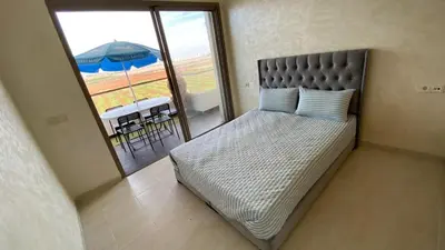 a bed in a room with a balcony with an umbrella at Puerto Banus Appartement A4 in Mohammedia