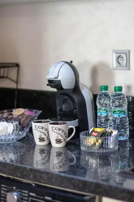 a coffee maker and two cups on a counter with water bottles at Studio chic et paisible avec piscine parc et plage in Aïn Harrouda