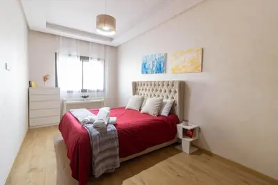 a bedroom with a red bed with a red blanket at Studio chic et paisible avec piscine parc et plage in Aïn Harrouda