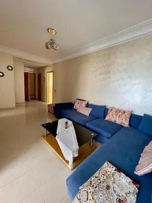 a living room with a blue couch and a table at Appartement Blanca Beach lumineux avec balcon in Sidi Rahal