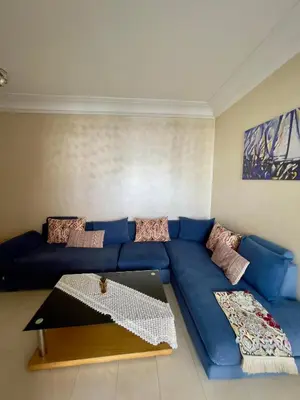 a blue couch in a living room with a table at Appartement Blanca Beach lumineux avec balcon in Sidi Rahal
