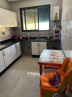 a kitchen with white cabinets and a table and a window at Bouznika mandarona in Bouznika