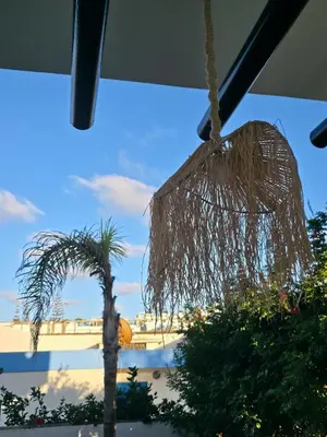 a palm tree and a straw hut hanging from a building at Seaside Artist's Villa in Temara