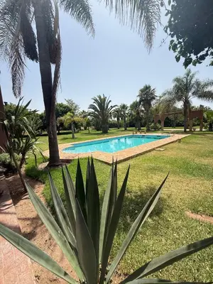 a palm tree and a swimming pool in a yard at Chic home with a private pool in Dar Mouddene
