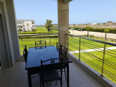 a table and chairs on a balcony with a view of a field at Ola Blanca in Dar Hamida