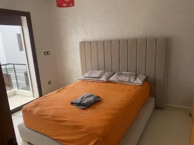 a bed in a bedroom with an orange sheet and a pillow at Villa pied dans l'eau in Sidi Rahal