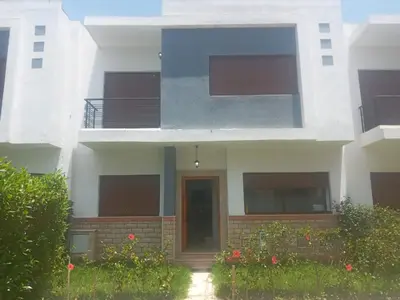 a white building with a door and some flowers at Villa pied dans l'eau in Sidi Rahal