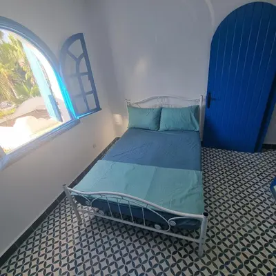a small bed in a room with a window at Private villa with pool in Bouznika