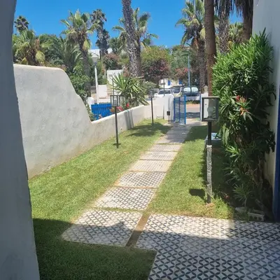 a walkway with grass and palm trees on a street at Private villa with pool in Bouznika