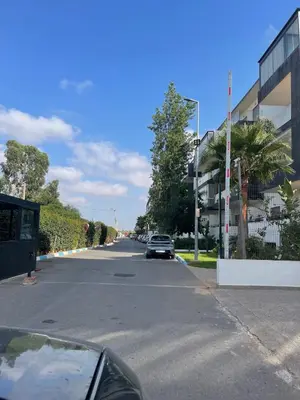 a car driving down a street next to a building at Cosy apartment in Bouznika in Bouznika