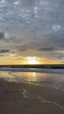 a beach with the sun setting on the water at Appartement à Ritaj Beach in Casablanca