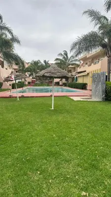 a yard with a swimming pool and a umbrella at Rayan beach Residence avec picine a tamaris in Tamaris