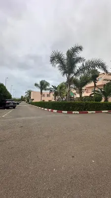 an empty street with palm trees and a building at Rayan beach Residence avec picine a tamaris in Tamaris