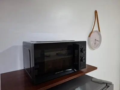 a microwave oven sitting on a wooden shelf with a clock at Apt 3 ch Casablanca 3 min Casa Voyageurs idéal pour une famille in Casablanca
