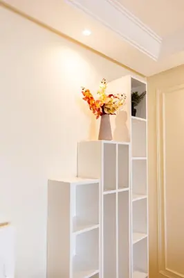 a white book shelf in a room with a vase with flowers at cozy living, Chic 3BR appartement with parking! in Casablanca