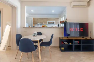 a dining room with a table and chairs and a tv at Luxury 2BR Apartment City Center with Parking in Casablanca