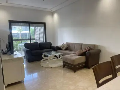 a living room with a couch and a table at Appartement Luxe Vue Piscine Résidence Les Perles de Bentriaa, El Mansouria in Mohammedia