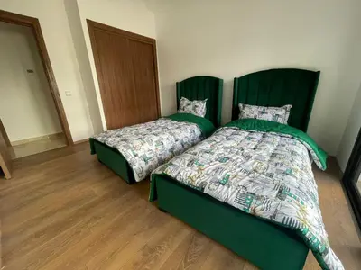 two beds sitting next to each other in a room at Appartement Luxe Vue Piscine Résidence Les Perles de Bentriaa, El Mansouria in Mohammedia