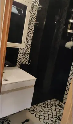 a black and white bathroom with a sink and a mirror at Le mataki in Mohammedia