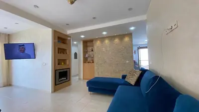 a living room with a blue couch and a tv at Puerto banus appartement in Mohammedia