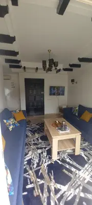 a living room with a table and a blue couch at Vue Mer & Sérénité, Appartement Chic avec Piscine à Dar Bouazza in Tamaris