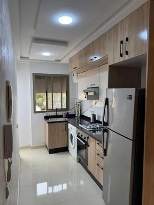 a kitchen with a white refrigerator and a stove at Cozy modern apartment 3 min drive beach access in Sidi Rahal