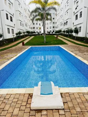 a swimming pool with a mattress in front of a building at Séjour Idéal à Tamaris Appartement Meublé Tout Confort in Tamaris