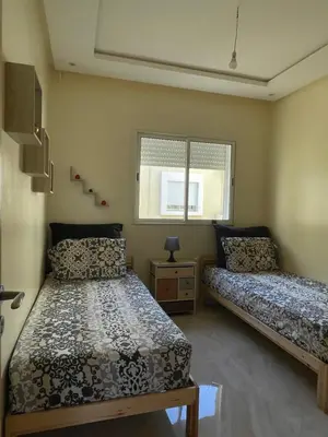 a bedroom with two beds and a window at lumineux appartement in Bouznika