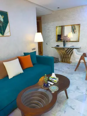a living room with a blue couch and a table at CASABLANCA BORD dE MER A 200 m DE LA PLAGE Appartement Haut de gamme 2 Chambres avec 2 Salles de bain Piscine Salle de Sport plage in Casablanca