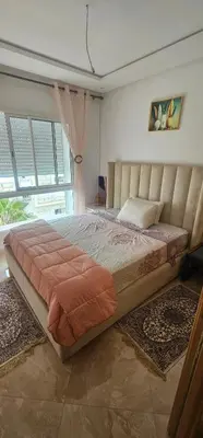 a large bed in a bedroom with a large window at Appartement vue sur piscine kettani in Bouznika