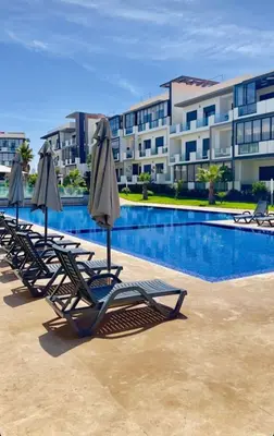 a row of lounge chairs with umbrellas next to a swimming pool at Dar Bouazza Plage in Dar Bouazza