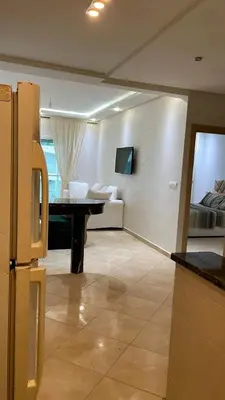 a kitchen with a table and a room with a bed at Appartement à Ritaj Beach in Dar Hamida