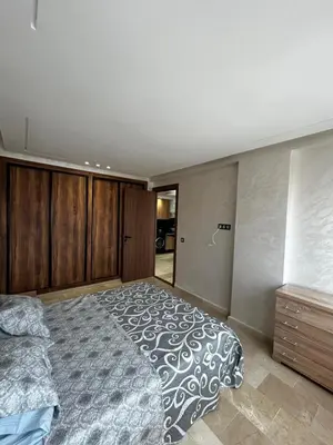a bedroom with a large bed and wooden cabinets at Nouvel Appartement Parc Mohammedia in Mohammedia