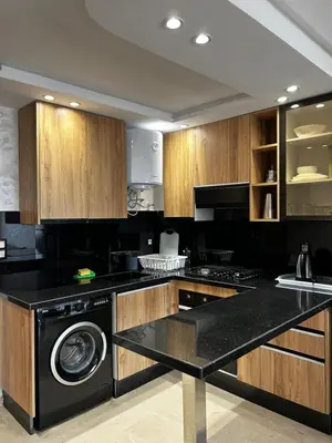 a kitchen with wooden cabinets and a black dishwasher at Nouvel Appartement Parc Mohammedia in Mohammedia