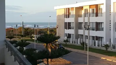 a building on a street with the ocean in the background at Bahía Golf Beach BOUZNIKA in Bouznika