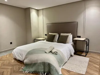 a bedroom with a large white bed with two tables at Duplex franceville in Casablanca