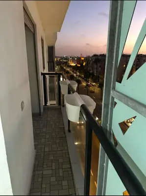 a balcony with white chairs and a view of a city at Superb appartement moyen standing au cœur de Aïn Sebàa in Casablanca