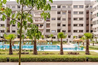 an apartment building with a pool and palm trees at 5 min from airport, 1 bedroom, balcony, pools in Nouaceur