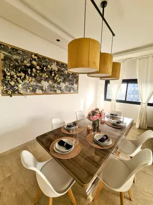 a dining room with a wooden table and white chairs at Duplex de Luxe avec Vue Mer a Zenata City-Eco in Aïn Harrouda
