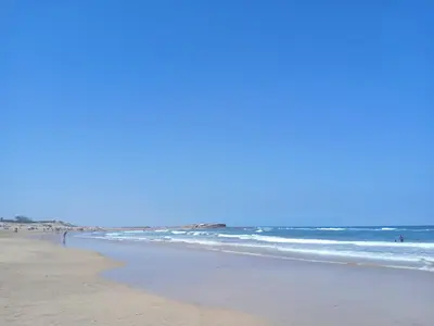 a beach with the ocean and people in the water at Duplex de Luxe avec Vue Mer a Zenata City-Eco in Aïn Harrouda