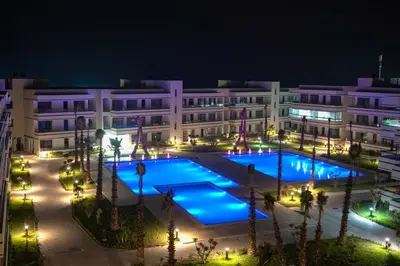 a building with a large pool at night at Résidence luxueuse avec 5 Piscine A MANSOURIA près de la Mer in O Ben Slimane