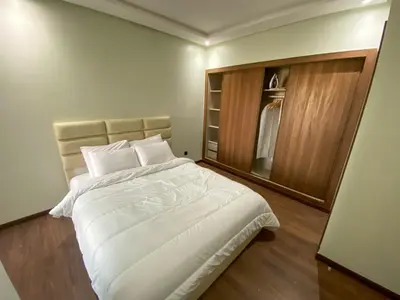 a bedroom with a large white bed and a closet at Résidence luxueuse avec 5 Piscine A MANSOURIA près de la Mer in O Ben Slimane