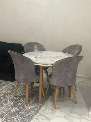 a table with four chairs and a bottle of water on it at Ocean park , for married couples and families only , Luxury fully furnished one bedroom flat next to zenata beach with five avialable swimming pool at the compound in Casablanca