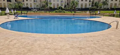 a large blue swimming pool in front of a building at Appartement avec piscine Bouznika in Bouznika