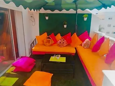a living room with an orange couch with colorful pillows at Appart avec piscine in Mohammedia